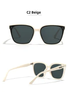 Detail of beige frame sunglasses featuring metal rivet studs and dark tinted lenses
