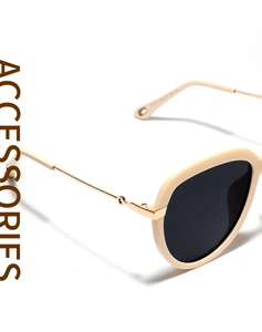 Détail de lunettes de soleil beiges avec branches en métal doré et gravures latérales