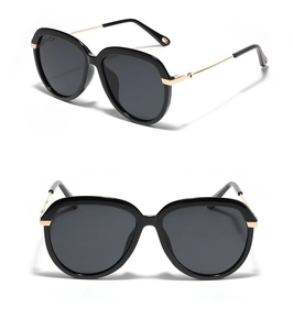 Détail de lunettes de soleil œil-de-chat noires avec branches dorées et verres foncés