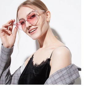 Close-up of a blonde model wearing stylish pink heart-shaped glitter sunglasses
