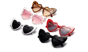 Flat lay detail showing five heart-shaped sunglasses in red, black, pink, and white