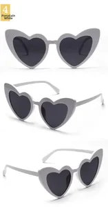 Three-way view of white heart-shaped sunglasses with gray lenses and detailed frame specs