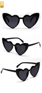 Detailed views of bright black oversized heart-shaped sunglasses with dark grey lenses