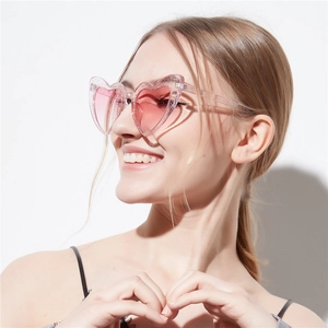 Stylish heart shaped sunglasses with pink glitter frames worn by a smiling model