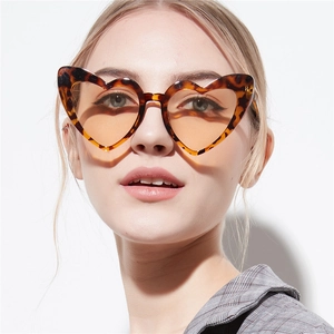 Stylish heart shaped sunglasses with leopard print frames and yellow lenses on a model