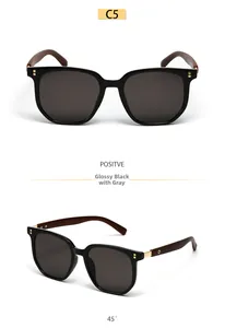 Detail of square black sunglasses featuring dark wood grain temples and gold hinges