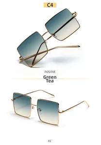 Detail view of large square gold metal sunglasses with green tea gradient lenses