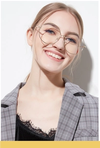 Detail of oversized gold round metal frame glasses worn by model for fashion style