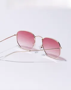 Detailed view of pink gradient lenses and sleek golden metal frames on square sunglasses