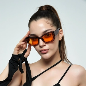 Y2K square sunglasses with translucent dark frames and orange lenses worn by a model