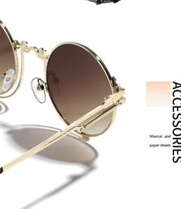 Detail shot of golden metal spring hinge and brown gradient lenses on round sunglasses