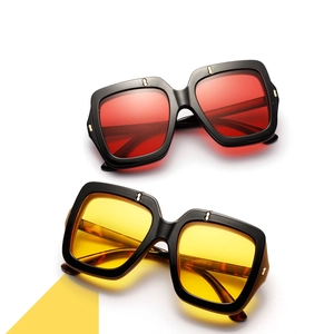 Close-up of square oversized sunglasses showing gold rivet details and dual-color lenses