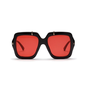 Close-up of black oversized square frame sunglasses with red lenses and gold metal studs