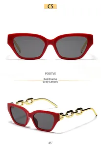 Detail of red square sunglasses featuring gold metal chain temples and grey lenses