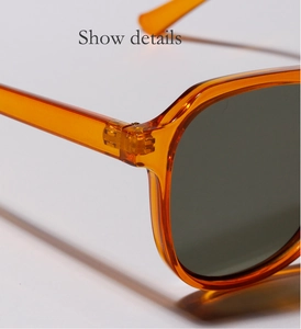 Detail view of the metal hinge structure on these orange transparent frame sunglasses