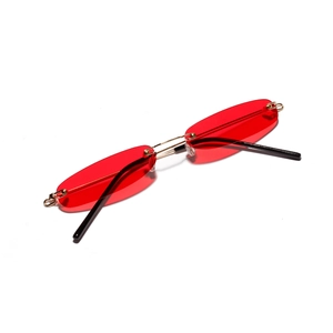 Rahmenlose ovale Sonnenbrille mit roten Meeresgläsern und goldenen Metallbügeln auf Weiß