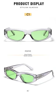 Detail of narrow cat eye sunglasses with transparent gray frames and green lenses