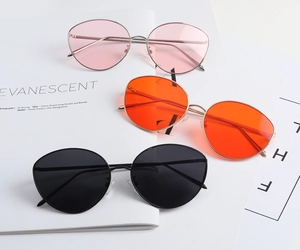 Trois paires de lunettes de soleil punk avec verres roses, orange et noirs sur fond blanc