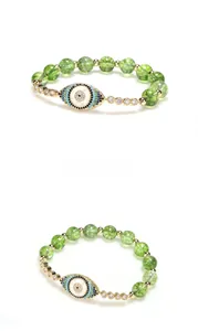 Macro detail of peridot beaded bracelet featuring an evil eye zircon pendant and gold finish