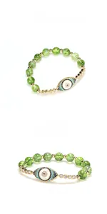 Macro detail of 8mm peridot bead bracelet with micro-paved cubic zirconia evil eye charm