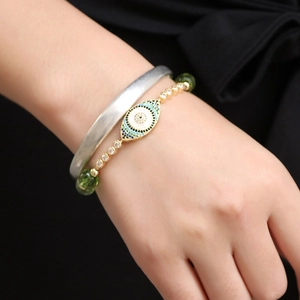 Golden Evil Eye bracelet with peridot beads and zircon stones on a model's wrist