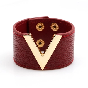 Detailansicht eines roten Lederarmbands mit einem polierten goldenen V-Logo aus Metall