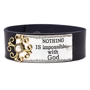 Détail d'un bracelet large en cuir noir avec plaque argentée gravée et relief doré