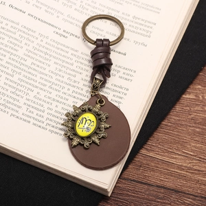 Vintage leather keychain with brass metal frame and tribal symbol on antique book background