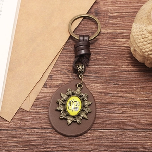 Handmade vintage leather keychain with bronze metal ring on dark wood surface