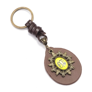 Vintage brown leather keychain with brass hardware and engraved yellow medallion on white base