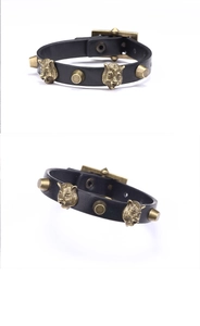 Nahaufnahme eines Punk-Lederarmbands mit bronzenem Tigerkopf und kegelförmigen Nieten