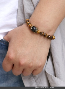 Gros plan détaillé du bracelet en perles d'oeil de tigre avec breloque couronne vintage