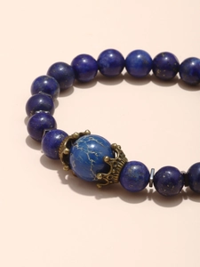 Vue macro des perles de lapis-lazuli bleu avec charmes couronne en bronze sur bracelet