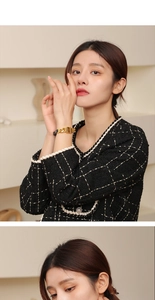 Gros plan d'un bracelet à grosse chaîne dorée porté avec une veste en tweed chic