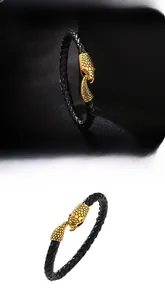 Detail of black braided leather bracelet featuring a golden snake head clasp with red eyes