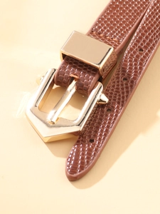 Close-up of tan lizard pattern leather strap and polished gold metal buckle