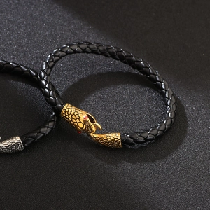Braided black leather bracelet featuring a gold snake head buckle with red stone eyes