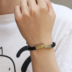 Men's leather wrap bracelet with golden snake heads and red accents on a braided band