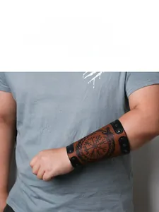 Macro view of brown leather punk wrist guard with Nordic compass and dragon engraving