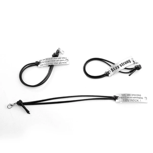 Three-piece set of woven leather inspirational bracelets with engraved metal tags on white background