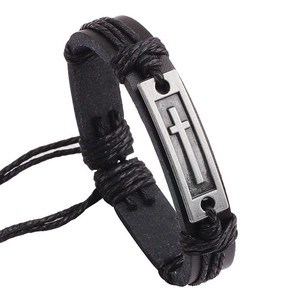 Detail of vintage black leather bracelet with an antique silver cross metal plate