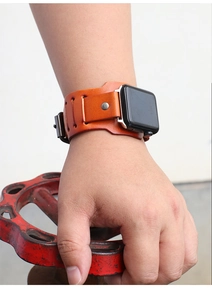 Macro detail of retro orange-brown leather cuff watch band with metal studs and stitching