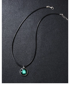 Detail of Libra zodiac pendant with green glow-in-the-dark starry glass and black cord