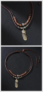 Macro detail of bohemian double feather pendant with ethnic wooden beads on braided rope