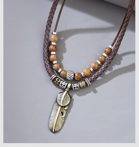Detail of vintage bohemian necklace with metallic feathers, wooden beads and woven cords
