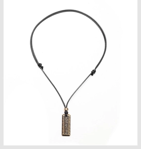 Détail du pendentif loup vintage avec écritures sur cordon en cire noire ajustable