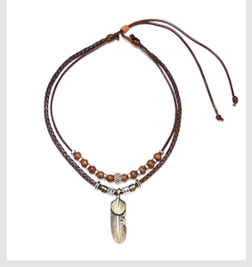 Detail of vintage bohemian necklace with metal leaf pendant and dark wood beads