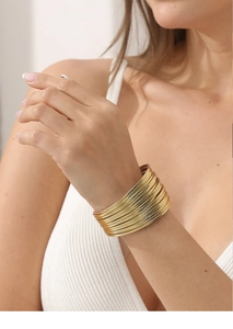 Close-up van een minimalistische goudkleurige metalen armbandenset om de pols