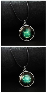 Close-up of glowing zodiac glass pendant necklaces with Taurus and Cancer motifs