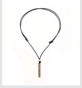 Détail d'un pendentif en métal vintage avec caractères tibétains gravés et cordon réglable